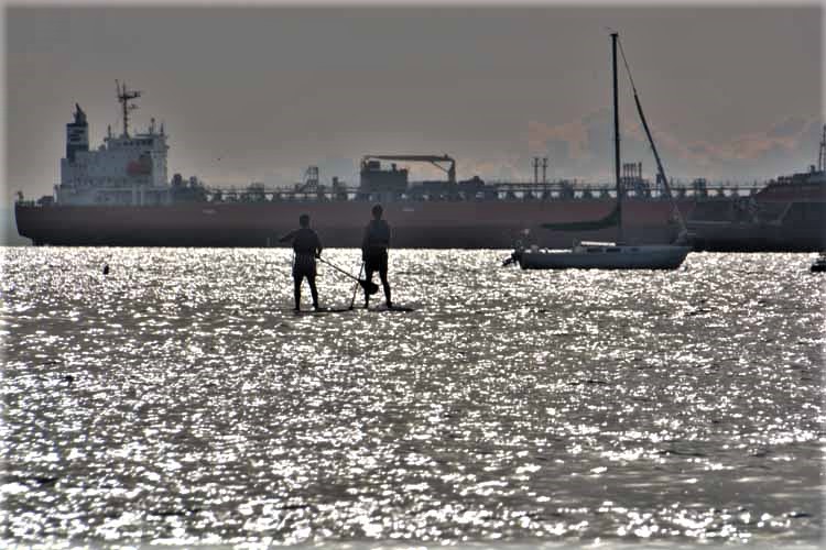 paddleboarders near freighter